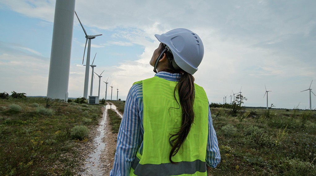 Engineer working in wind turbines farm on a rainy day. Renewable energy systems.