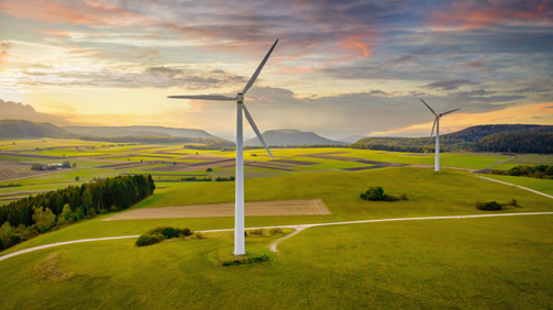 Aerial drone point of view of modern wind turbines in green rural landscape during a colorful sunset twilight. Green Energy, Alternative Energy Environment Concept Shot. Baden Württemberg, South Germany, Europe