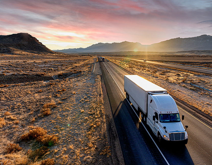 White Semi-Trailer Truck Heading down a four-lane Highway at Dusk delivering a load in the southeastern Utah desert on interstate 70 east bound