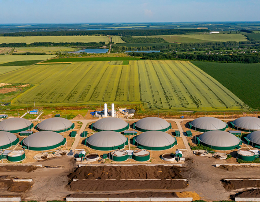 Green biogas plant storage tanks. Aerial view over biogas plant and farm in green fields. Renewable energy from biomass. Modern agriculture concept