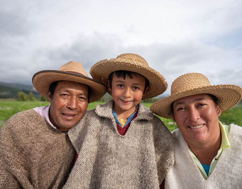 Portrait of a happy Latin American family harvesting the land wearing hats and a ruana and looking at the camera smiling â agricultural lifestyle concepts