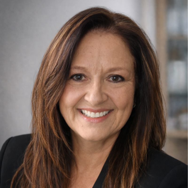 Smiling woman with shoulder-length brown hair wearing a black blazer; head-and-shoulders professional portrait.