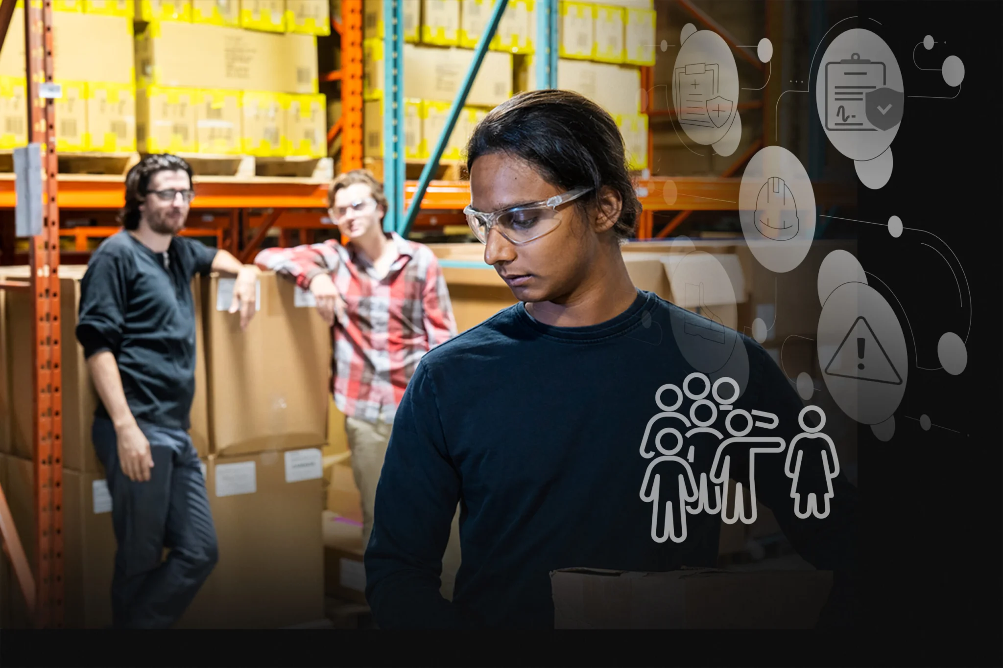 Warehouse workers in safety glasses standing among stacked boxes; foreground person looks down, carrying a box; abstract icons overlay on the right side conveying safety tech.