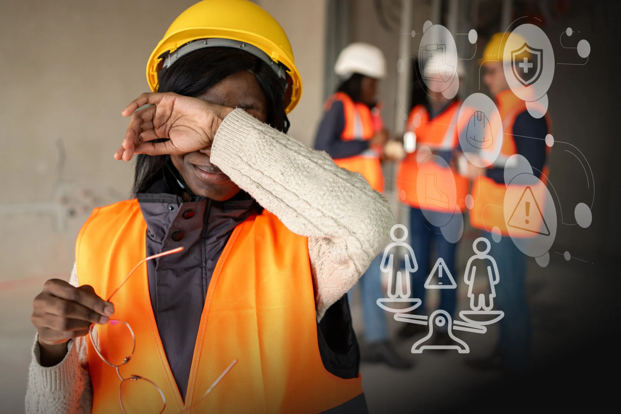 Construction worker shielding eyes in an orange safety vest and yellow helmet; colleagues in hi-vis vests in the background.